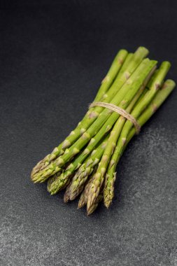 Koyu bir yüzeye yerleştirilmiş taze yeşil kuşkonmaz..