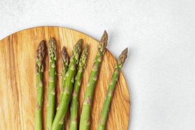 Yeşil kuşkonmaz mızrakları yuvarlak ahşap bir tahtaya yerleştirilmiş yemek için hazırlanıyor..