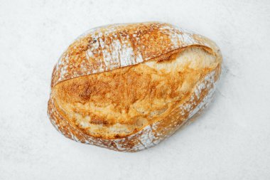 Kırsal ekşi ekmek, sıcak bir mutfak ortamında hafif bir yüzeye dayanır..