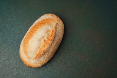 Taze pişmiş rulo, altın kabuklu ve yumuşak dokusuyla karanlık bir yüzeye dayanır..