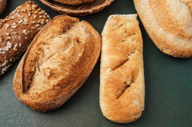 Bir yüzeyde gösterilen farklı ekmek türleri, çeşitlilik ve doku gösterimi.