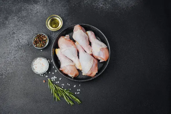 Siyah kasede çiğ tavuk budu ve baharat.