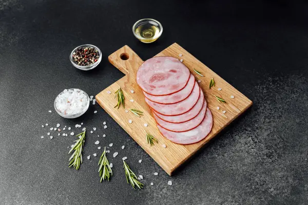 Siyah masa arkasında tuzlu ve biberiyeli dilimlenmiş domuz sosisi.