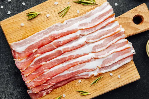 Siyah yüzeyde baharat ve biberiye ile sıralanmış jambon dilimleri.