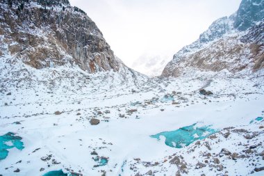 Chamonix 'de karlı, kayalı ve mavi buzul havuzlu donmuş alp vadisi