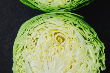 Karanlık arka planda iki kesik lahana parçası. Yakın plan.