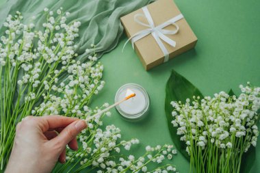 Vadideki zambak ve yeşil arka planda hediye kutusuyla çevrili el feneri.