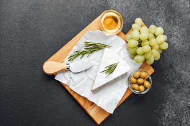 Lezzetli bir atıştırmalık için krem peynir, üzüm, zeytin ve biberiye tabağı.