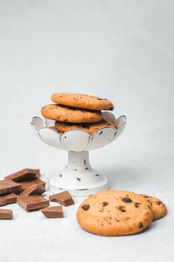 Çikolata parçalı kurabiyeler dağınık çikolata parçalarının yanında duruyor..