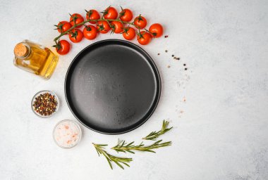 Domates, biberiye, tuz, yağ ve biber içeren yemek malzemelerinin olduğu boş siyah tabağın üst görüntüsü
