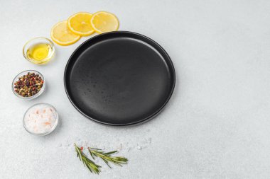 Parlak limonlar ve bitkiler bir yüzeyde yağ ve baharatların yanında dizilmiştir.