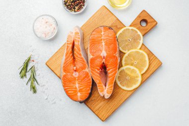 Somon filetoları, limon dilimleri ve baharatlarla birlikte ahşap bir tahtaya konur..