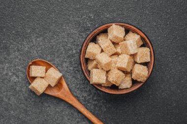 Kahverengi şeker küpleri özenle koyu arkaplandaki ahşap bir kasede düzenlenir..