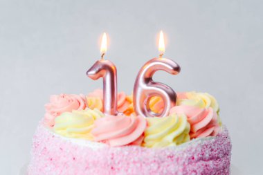 Pembe ve sarı şekerli bir pasta 16. yaş günü için mumlar içerir..