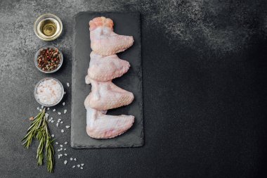 Siyah tahtada çiğ tavuk kanadı ve baharat.
