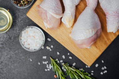 Ahşap tahtada çiğ tavuk budu ve baharat.