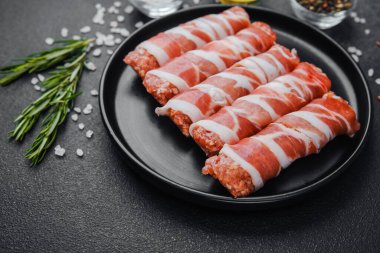 Domuz pastırmasına sarılı çiğ et ruloları ve baharatlar.