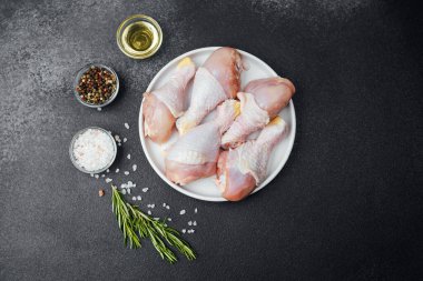 Tavuk budu çiğ, baharatlı ve otlu beyaz tabakta.