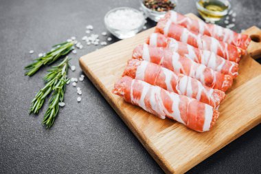 Pastırmaya sarılı çiğ et ruloları ahşap tahtaya baharatlı.