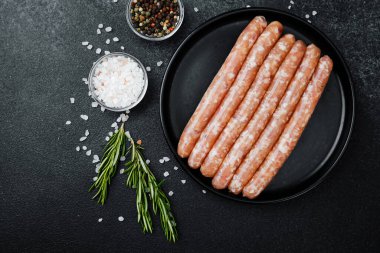 Siyah tabakta çiğ domuz sosisi ve biberiye.