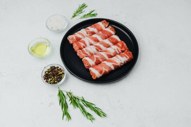 Domuz pastırması siyah tabakta baharat ve biberiye ile sarılmış.