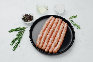 Siyah tabakta taze domuz sosisi, biberiye ve tuz.