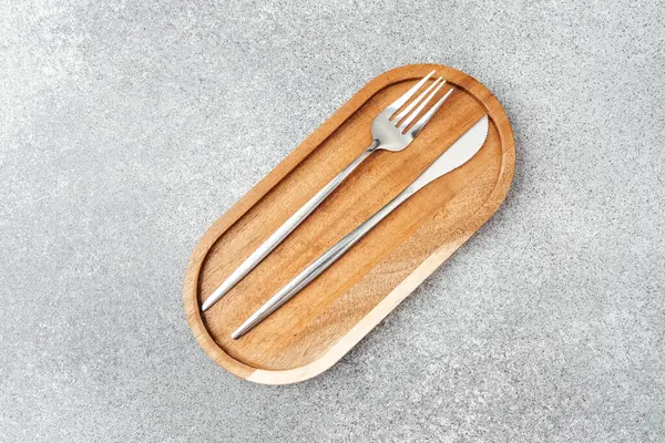 Modern çatal bıçak takımı ahşap servis tepsisine yerleştirilmiş, yemek için mükemmel..