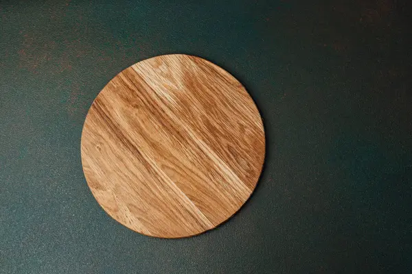 Koyu arkaplan üzerine kurulmuş yuvarlak ahşap bir tahta yemek hazırlamak için ideal..