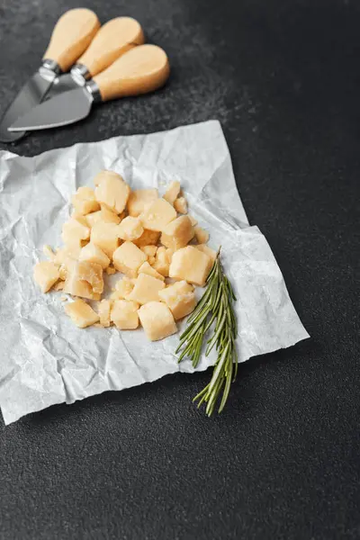 Yanında biberiye filizleri olan parşömenin üzerine yerleştirilmiş küçük peynir parçaları..