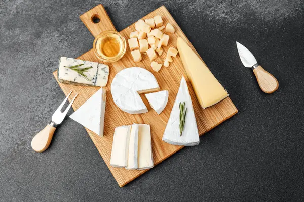 Farklı peynir ve aletlere sahip güzel bir peynir tahtası..