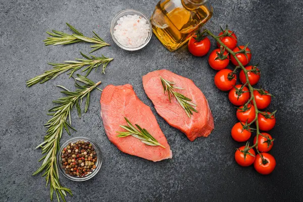 Siyah arka planda biberiyeli taze çiğ biftek ve tuz ve baharat.