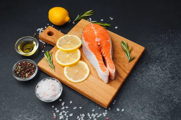 Limon dilimleri ve otlarla birlikte kesilmiş somon filetosu..