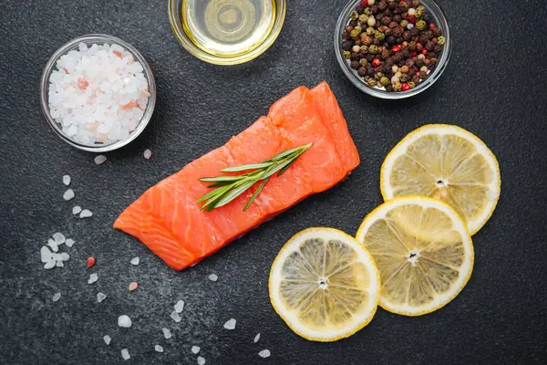 Parlak somon filetosu otlarla süslenmiş ve limon dilimleri pişirmeye hazır..