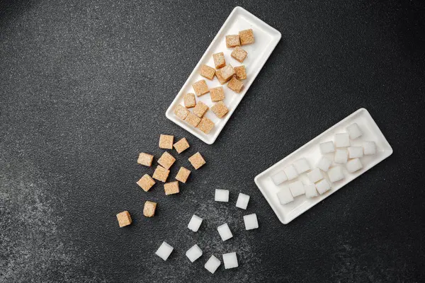 İki tip küp şeker, beyaz tepsiler üzerinde siyah bir zemin üzerinde düzgün bir şekilde düzenlenir..