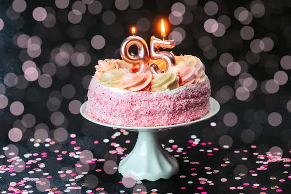Güzel dekore edilmiş pembe pasta, bir dönüm noktasını iki mumla kutluyor..