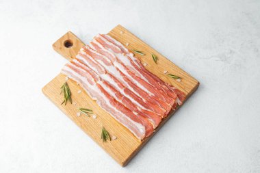 Ahşap tahtada çiğ pastırma dilimleri, biberiye ve koyu arkaplanda tuz.