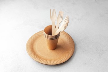 Beyaz arka planda tek kullanımlık tabakta ahşap çatallı eko kağıt bardaklar.