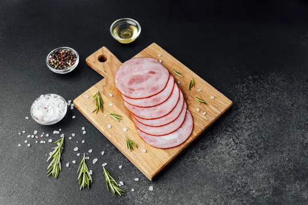 Siyah masa arkasında tuzlu ve biberiyeli dilimlenmiş domuz sosisi.