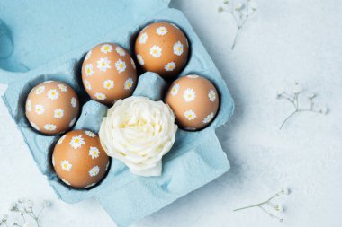 Papatya süslemeli Paskalya yumurtaları ve mavi kartonda beyaz gül. Makro Paskalya detayı arkaplanı.