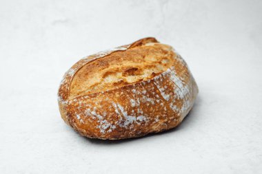 Dış görünüşü altın-kahverengiye boyanmış yuvarlak ekmek, tarafsız bir zemine dayanır..