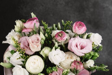 Taze hazırlanmış buket pembe güller, beyaz ranunculus ve yeşillik içerir..
