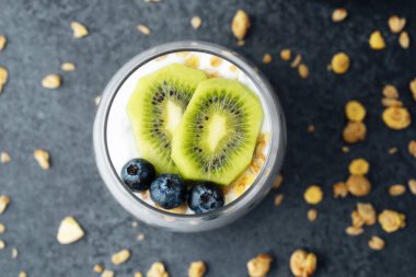 Koyu arkaplanda kivi ve yaban mersinli sağlıklı kahvaltı.