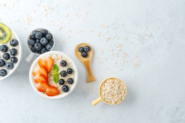 Beyaz arka planda çilekli yulaf ezmesi ve yaban mersini.