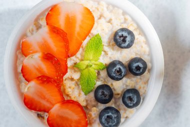 Yulaf ezmesi kasesini çilek ve nane ile kapat.