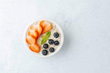 Beyaz arka planda yulaf ezmesi, çilek ve yaban mersini manzarası