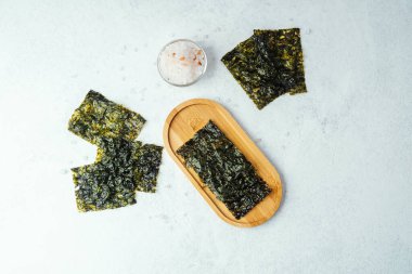 Beyaz arka planda bir kase tuzlu kavrulmuş yosun atıştırmalığı