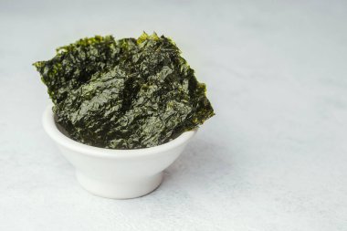 Tahta tahtada kızarmış Norveç yosunu ve beyaz ve yeşil arka planda seramik kase.