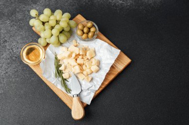 Bir peynir tabağında atıştırmak için doğranmış peynir, üzüm, zeytin ve bal yer alır..