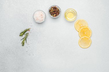 Dilimlenmiş limon ve bitkiler tezgahta baharat ve yağın yanına konur..