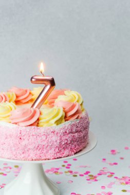 Pembe ve sarı kremalı canlı bir pasta yedinci yaş gününü kutlar..